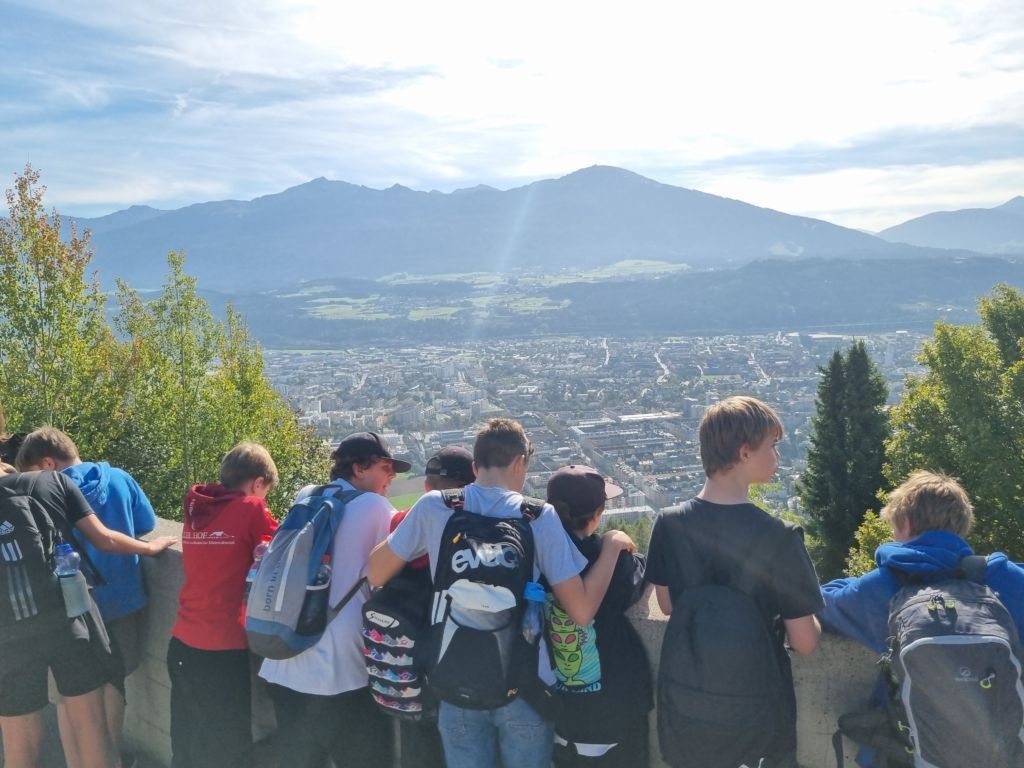 Schüler*innen stehen mit dem Rücken zur Kamera, im Hintergrund ist Innsbruck zu erkennen